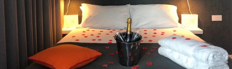 Romantic bedroom showing rose petals scattered across the bed plus a bottle of Champagne on ice