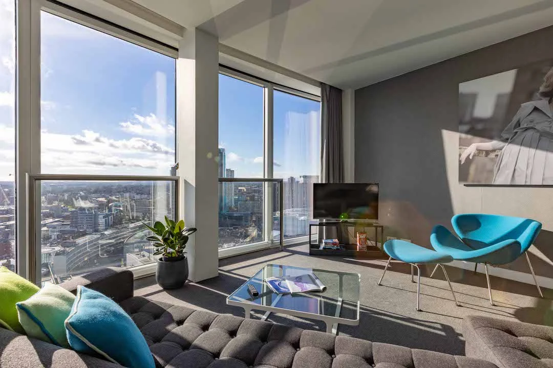 Staying Cool's Clubman apartment living space with floor to ceiling windows and city views