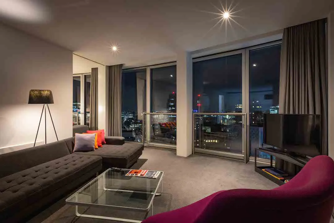 Staying Cool's maxi apartment living space with floor to ceiling windows with city views at night