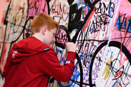 Teen drawing on wall at B Side Hip Hop Festival taken by Joe Bailey
