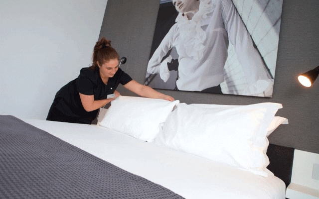 Housekeeper making bed at Staying Cool at the Rotunda. 