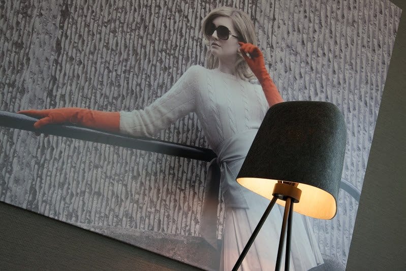 Eco tourism. Grey Tom Dixon lamp in front of 1960s inspired photogrpah of a model 