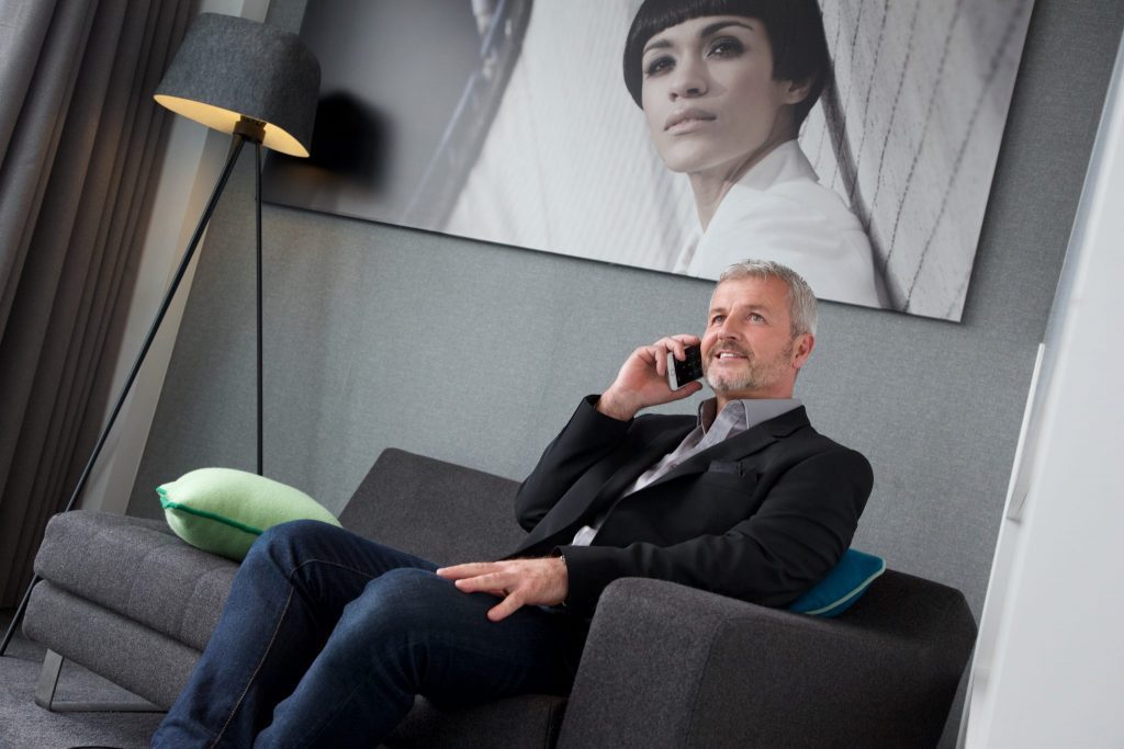 Man on business travel sitting on charcoal sofa in serviced apartment