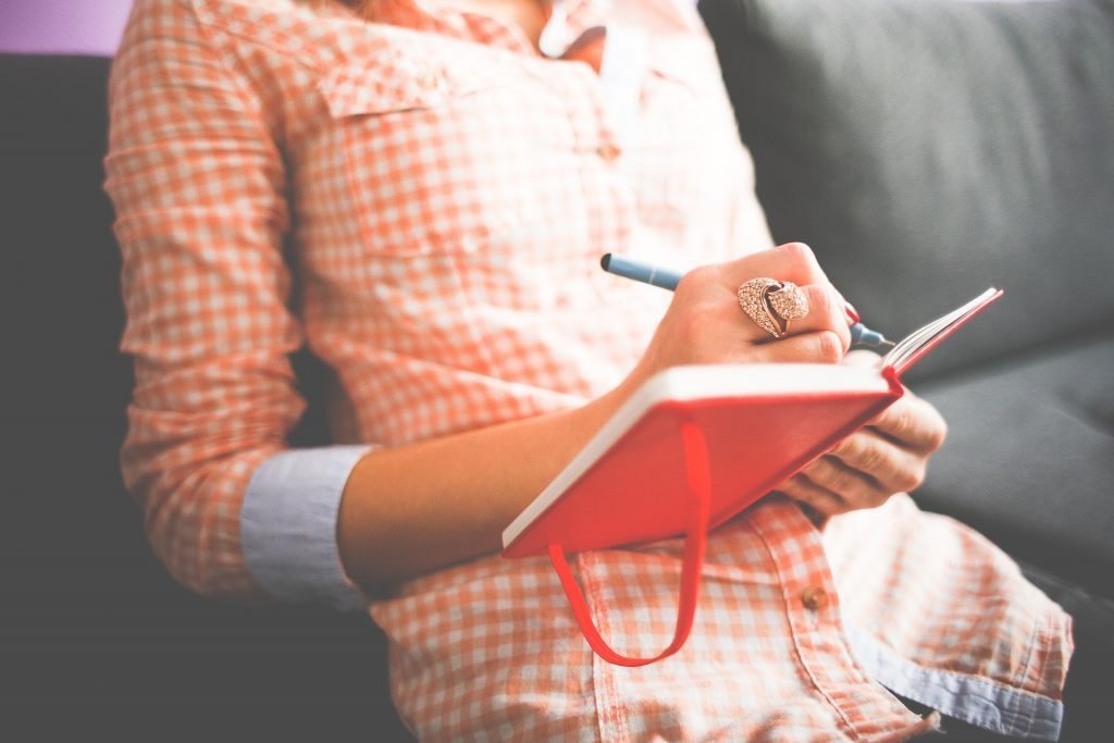 Woman writing in notebook. Business travel planning.