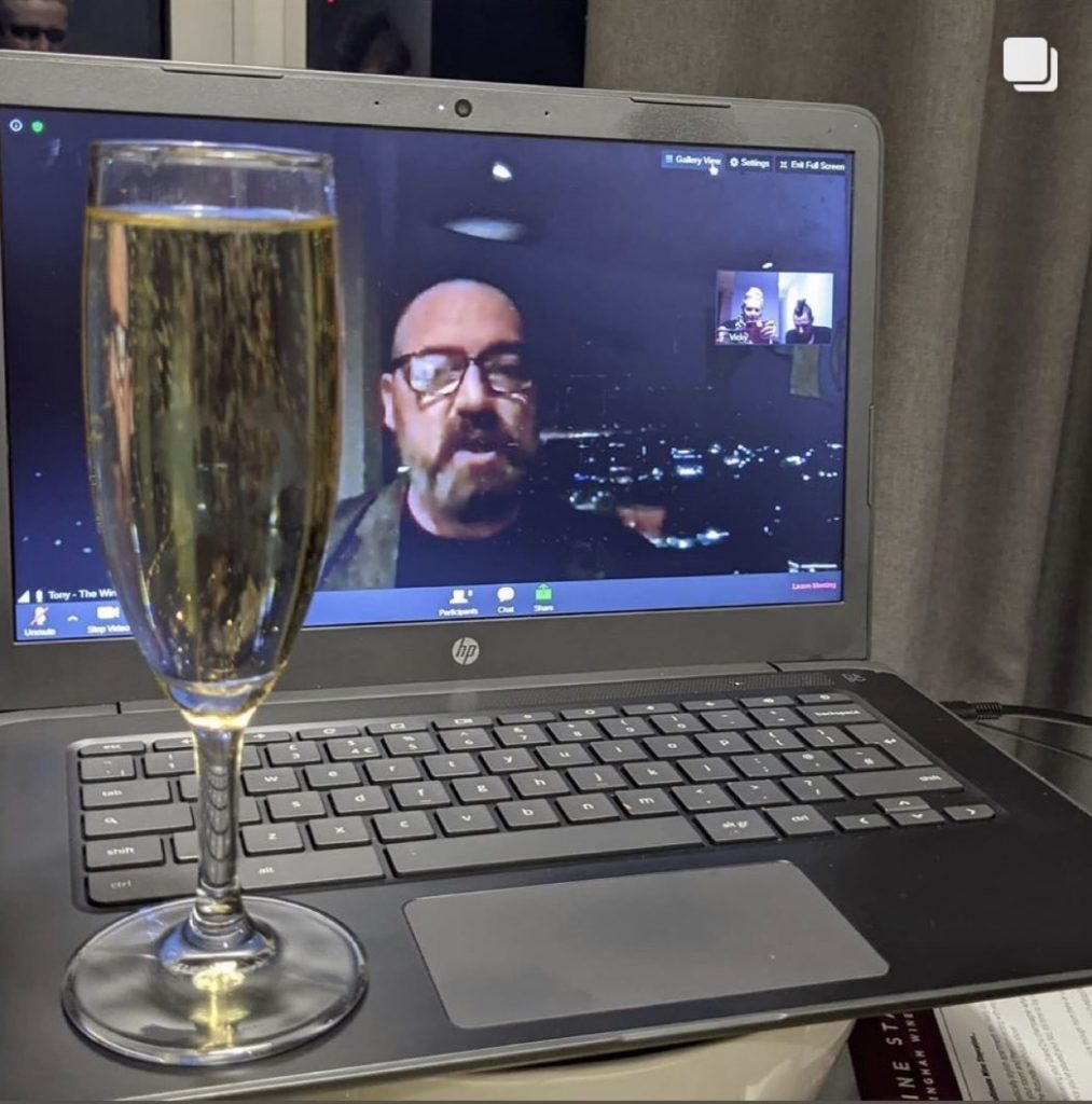 Glass of champagne in front of zoom call with Tony Elvin on screen presenting The Wine Staycation event at Staying Cool's Rotunda Aparthotel