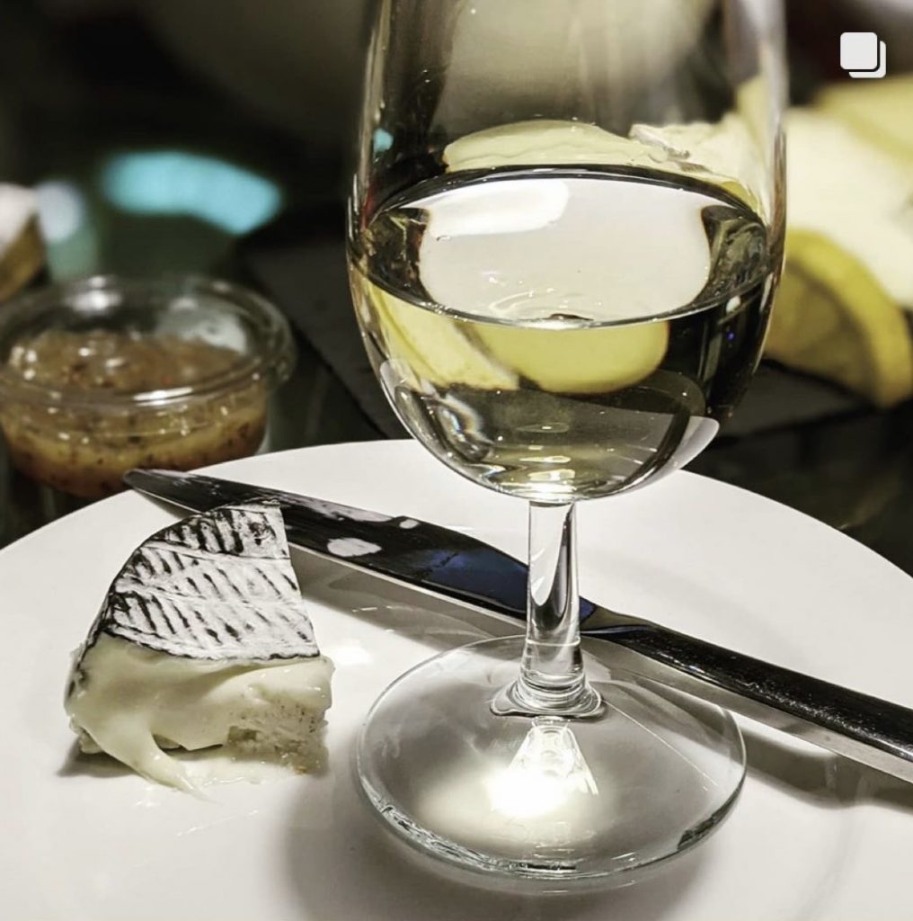 Glass of white wine and smoked cheese on a plate at The Wine Staycation event at Staying Cool's Rotunda Aparthotel