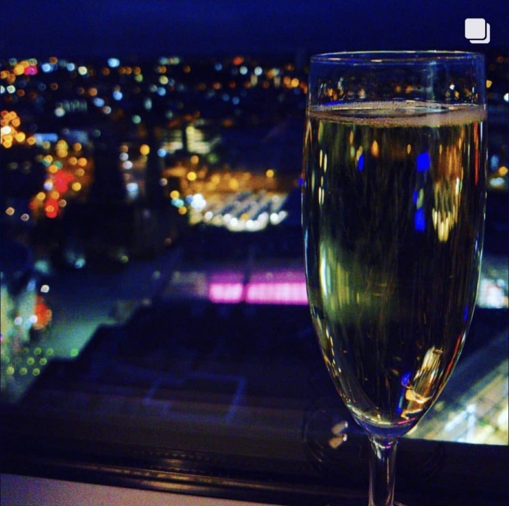 Glass of champagne with Birmingham city lights in the background taken from Staying Cool's Rotunda Aparthotel