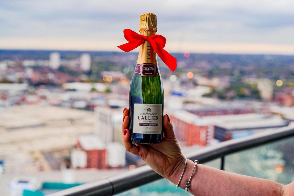 Bottle of Lallier Champagne with city views taken from Staying Cool's Rotunda Aparthotel penthouse balcony.