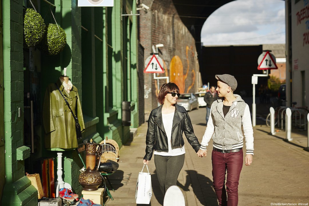 Couple holding hands walking down street outside of the Custard Factory in Digbeth Birmingham