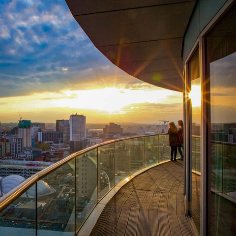 Two guests enjoying the city sunset views from Staying Cool's Rotunda penthouse balcony.